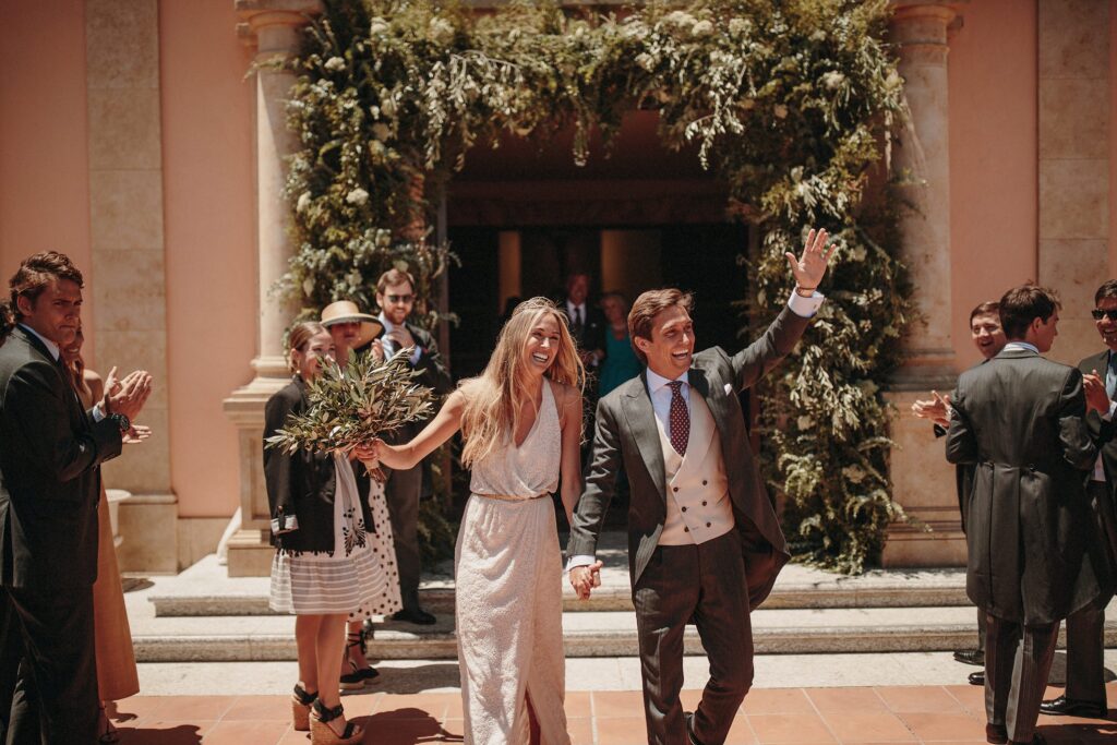 Natalia y Diego saliendo bajo el arco de flores